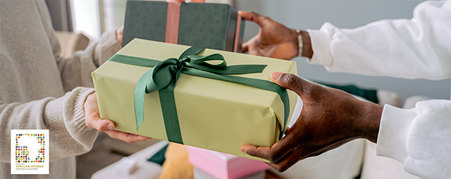Two people are exchanging gifts between them. Both gifts are gift-wrapped and have ribbons tied into bows. The image is tightly focused on the arms holding the gifts.