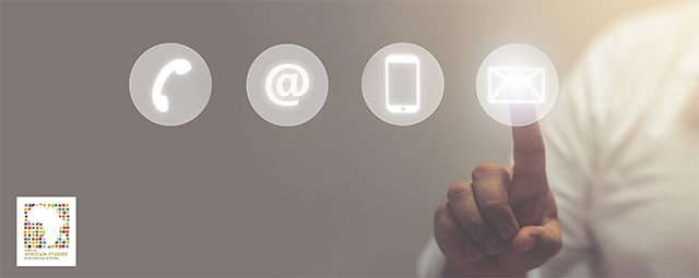 Icons that represent methods of communication are displayed on a clear touch screen. A person is using their index finger to interact with this touch screen to select the icon shaped like an envelope.